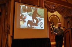 Michael Horn giving a seminar on 29 May 2011. Meier is pictured on the screen behind him, departing for a contact on his motorbike. Source